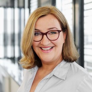 Portraitbilder von Claudia Baumer, Prokuristin und VP Business Development bei der acoris AG, mit blonden Haaren und einer Brille